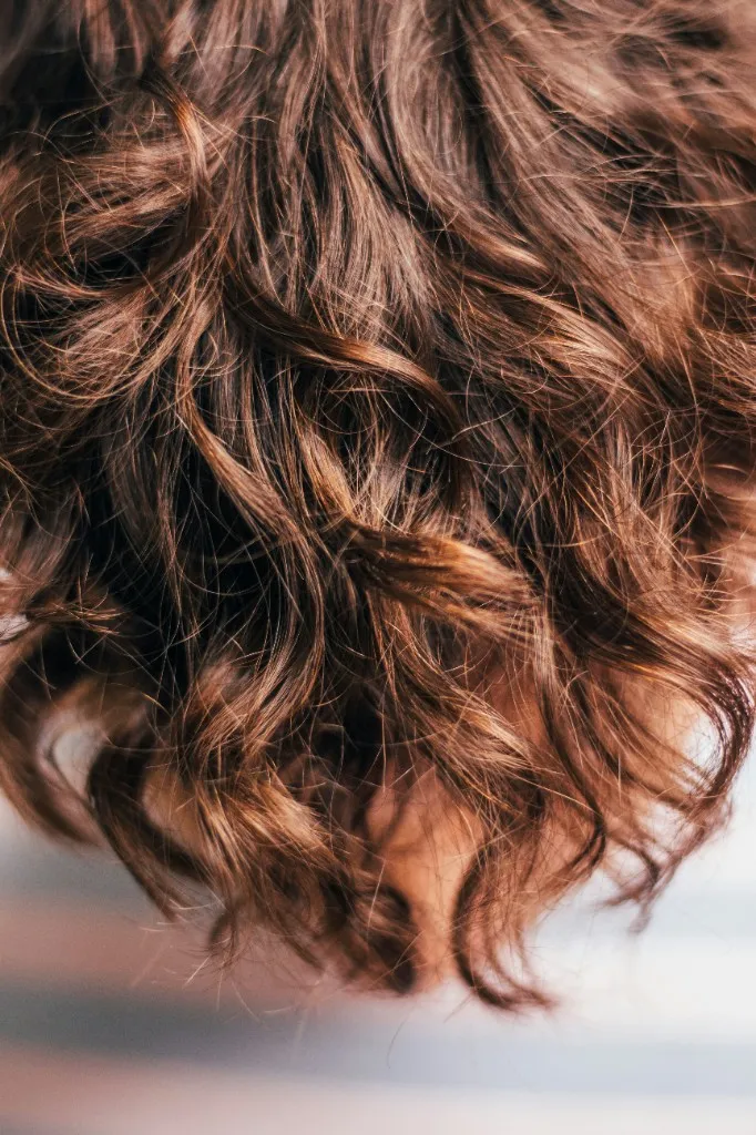 Cabello castaño ondulado, visto de cerca.
